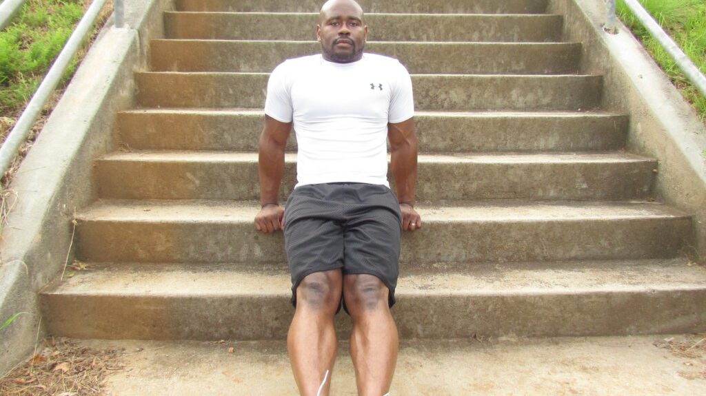 Lenox Wilson performing triceps exercise using stairs