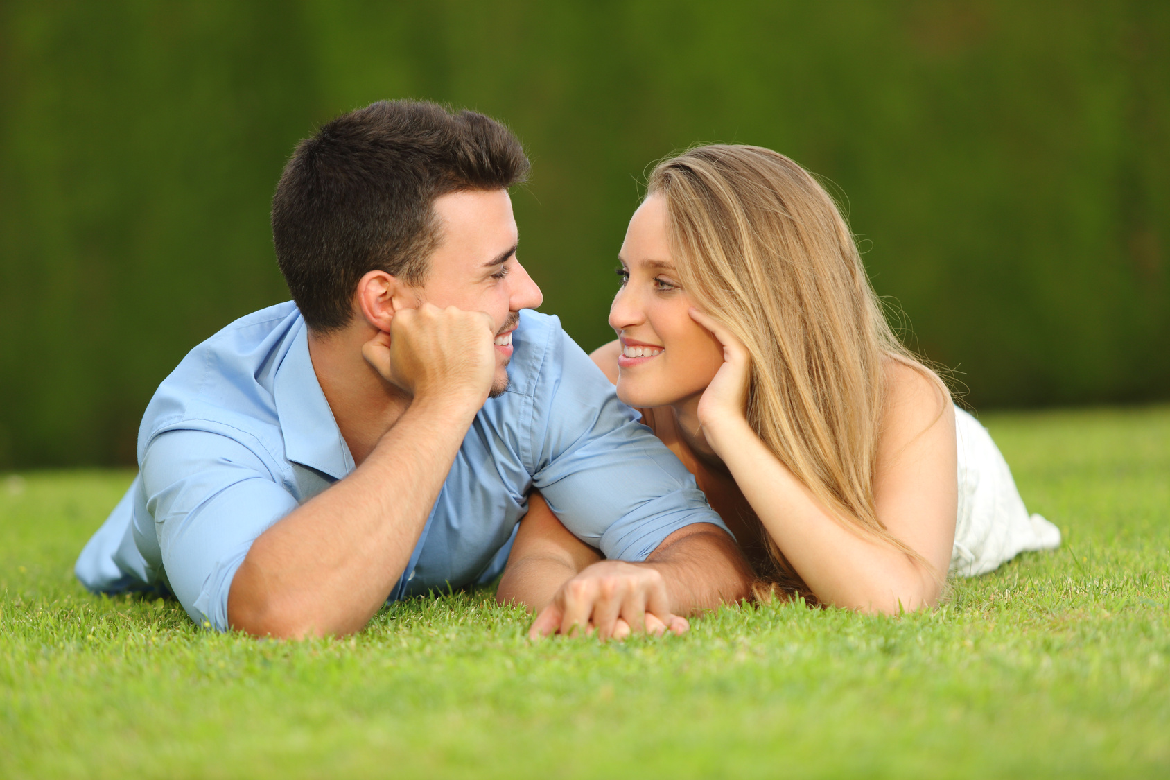 Man and woman lying on the grass looking into each other's eyes